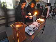 御蔵小学校で東遊園地の「希望の灯り」から分灯した火をもらい、ろうそくに灯をともす作業をする 2010年1月17日)